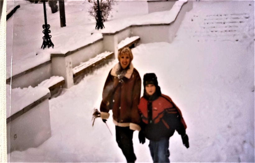 Eine tief verschneite Wiese, auf der eine Frau mit ihrem Sohn durch den Schnee stapft.